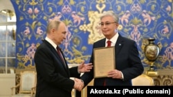 Президент России Владимир Путин вручает президенту Казахстана Касым-Жомарту Токаеву наградной лист его отца Кемеля Токаева. Москва, 9 мая 2025 года