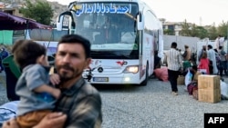 له ایرانه ویستل شوی یو افغان کډوال له هراته د کابل په لوري په بس کې سفر ته ځان چمتو کوي - د جولای ۱۶مې انځور 