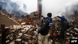 Members of the OSCE's Special Monitoring Mission to Ukraine take pictures of a destroyed house in Avdiyivka after heavy shelling by pro-Russia separatists