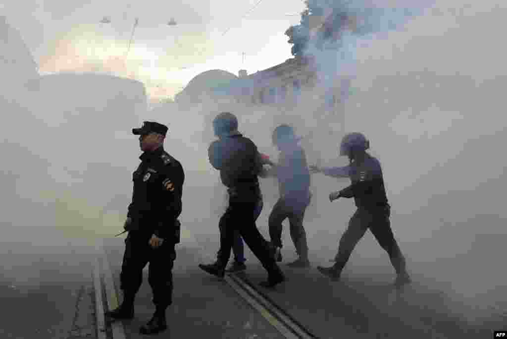 A protester is led away through clouds of smoke in St. Petersburg.&nbsp;