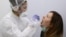 RUSSIA -- A health worker wearing protective gear takes a swab from a woman to test for the coronavirus disease (COVID-19) at Gemotest laboratory in Moscow, April 6, 2020