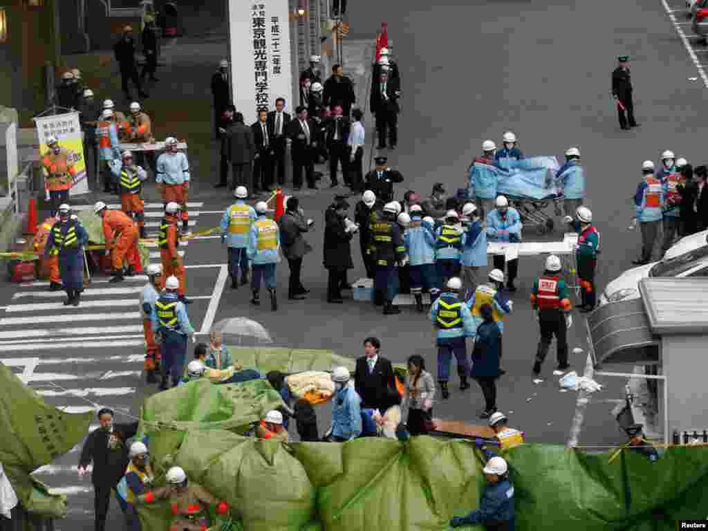 Japan--Rescue workers hurry to a building following reports of injuries in Tokyo's financial district after an earthquake off the coast of northern Japan, 11Mar2011 - Спасатели оказывают помощь пострадавшим в финансовом районе Токио после землетрясения у берегов северной Японии 11 марта 2011. REUTERS / Kim Kyung-Hoon