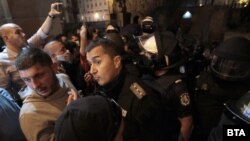 Напрежението между полицаи и протестиращи във вторник в София ескалира, след като група младежи с качулки атакуваха входа на втората сграда на парламента с бомбички, боя, камъни и бутилки със запалителни течности