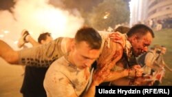 Протестиращи носят ранен от полицията човек късно през нощта на 9 август 2020 г. след избухването на антиправителствените протести в Беларус.