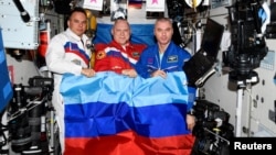 Russian cosmonauts onboard the International Space Station pose with a flag of separatist forces in Luhansk, Ukraine, on July 4.