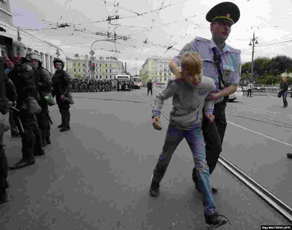 A child is led away by a police officer during a protest in St. Petersburg.&nbsp;