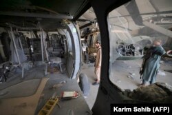 Талиб согушкерлери Кабул аэропортундагы ангарда Ооган аскердик аба күчтөрүнүн жабыркаган тик учактарынын жанында турат. 14-сентябрь, 2021-жыл.