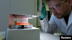 Германиялык биофармкомпаниянын кызматкери COVID-19га каршы вакцинаны сыноодон өткөрүп жатат. 