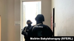 Orda.kz habar merkeziniň girelgesiniň öňünde duran polisiýa işgärleri. Almaty, 2025-nji ýylyň 1-nji dekabry