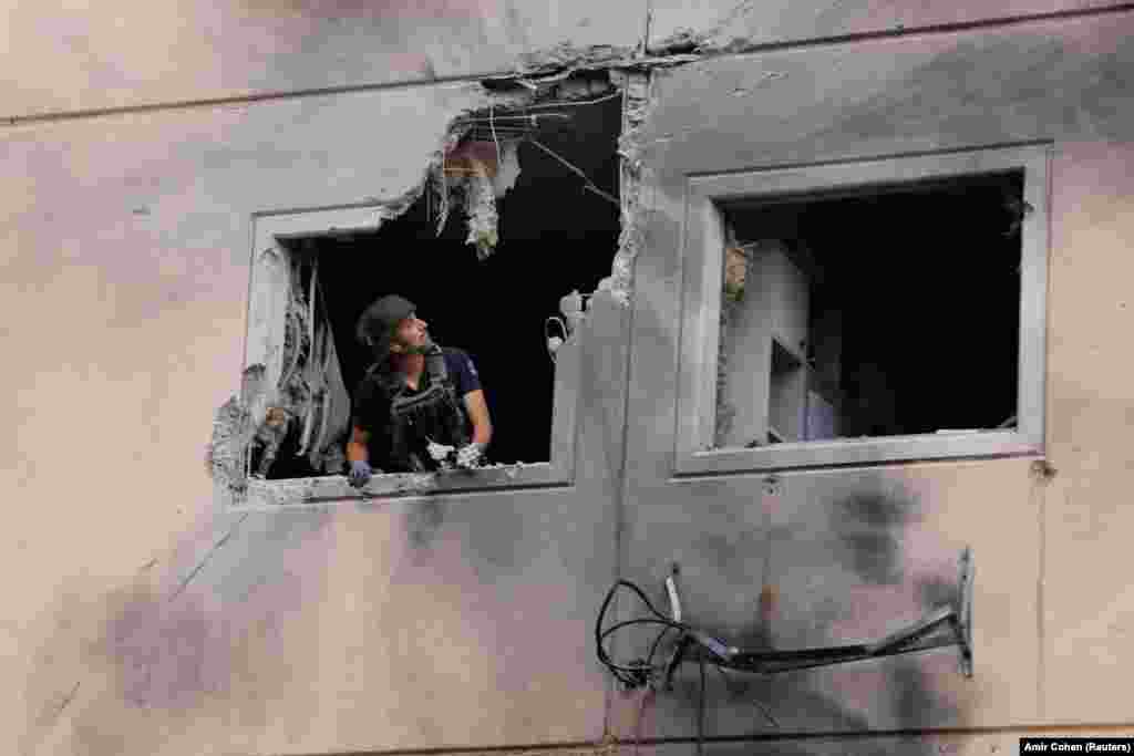 Експерт із питань утилізації бомб ізраїльської поліції виглядає з вікна житлового будинку, який був пошкоджений після удару ракетою, випущеною зі Смуги Газа, в Ашкелоні, на півдні Ізраїлю, 11 травня 2021 року