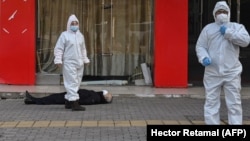 Медработники в защитных костюмах эвакуируют умершего на улице в Ухане рядом с одной из местных больниц, 30 января 2020 года
