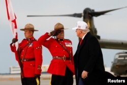 Un ofițer al Poliției Regale Călare a Canadei salutând, în momentul în care președintele american, Donald Trump, coboară din avion la sosirea sa în Canada, pe 15 iunie, înainte de întâlnirea liderilor G7 la Kananaskis