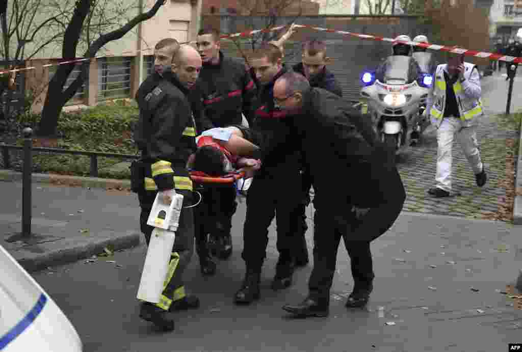 A victim is evacuated on a stretcher outside the publication's offices.